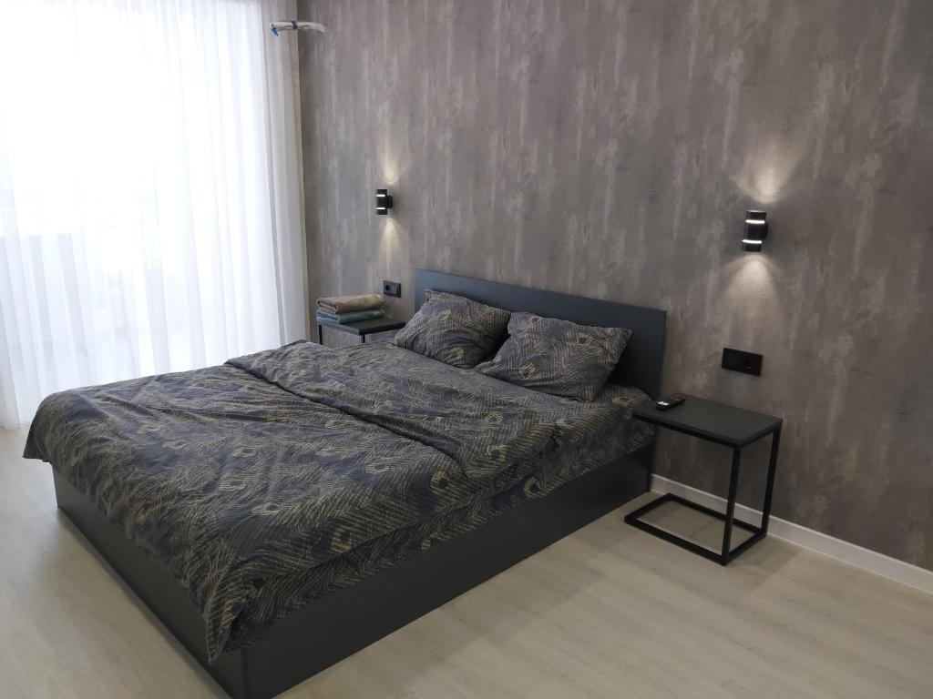文尼察Люкс Апартаменты Gray Pearl на Подолье的一间卧室配有一张床和一张边桌
