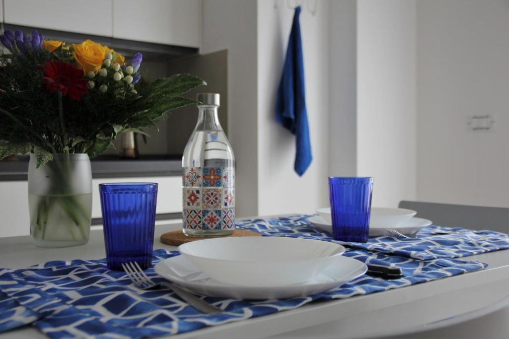 斯培西亚New apartment close to the Cinque Terre的一张桌子,上面有盘子和蓝玻璃杯,还有一瓶