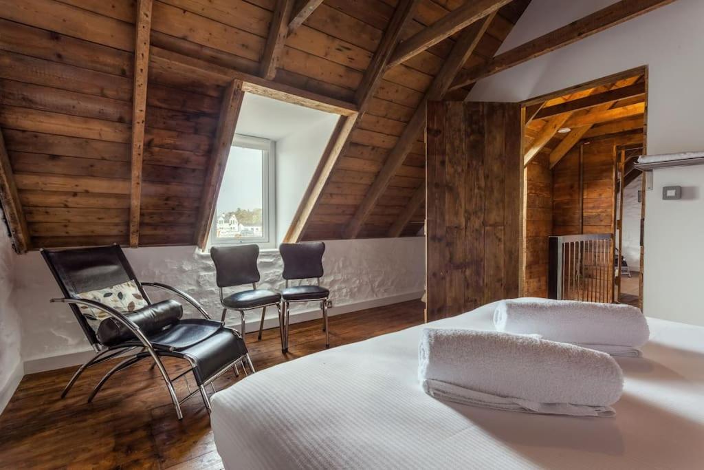 凯里肯Isle of Skye Cottage的一间带床和椅子的卧室,位于带木制天花板的房间内