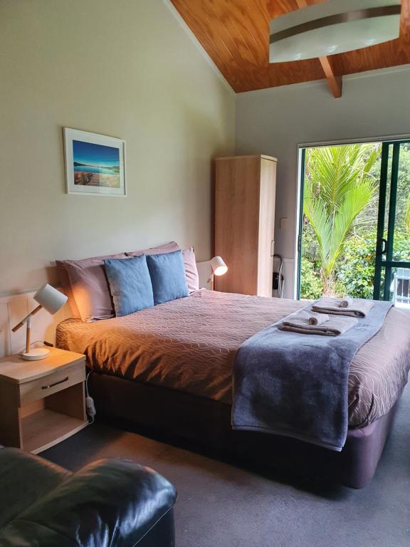 Kaihu贝壳杉海岸十大假日公园 的一间卧室设有一张大床和一个大窗户