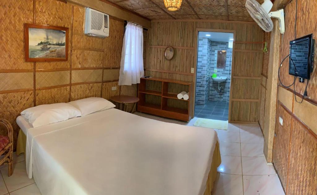 波尔多·格尼拉Bamboo House Beach Lodge & Restaurant的一间带白色床的卧室和一间浴室