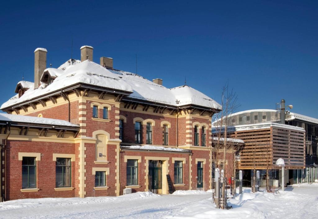 利勒哈默尔Lillehammer Stasjonen Hostel的一座大砖砌的建筑,上面有雪