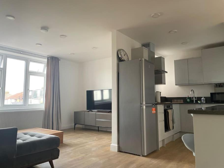 WansteadFamily friendly new flat at London Gants Hill Station near Ilford的厨房以及带冰箱的起居室。