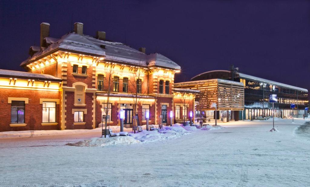 利勒哈默尔Lillehammer Stasjonen Hotel的夜间积雪中被点燃的建筑物