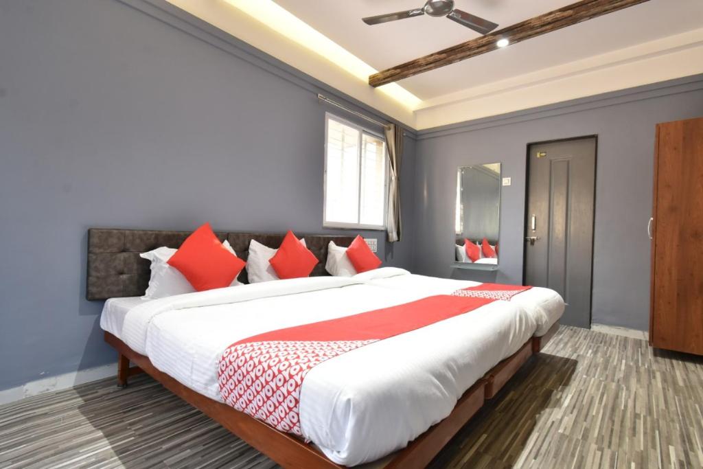 索拉普Hotel Ashirwad, Solapur的一间卧室配有一张带红色枕头的大床