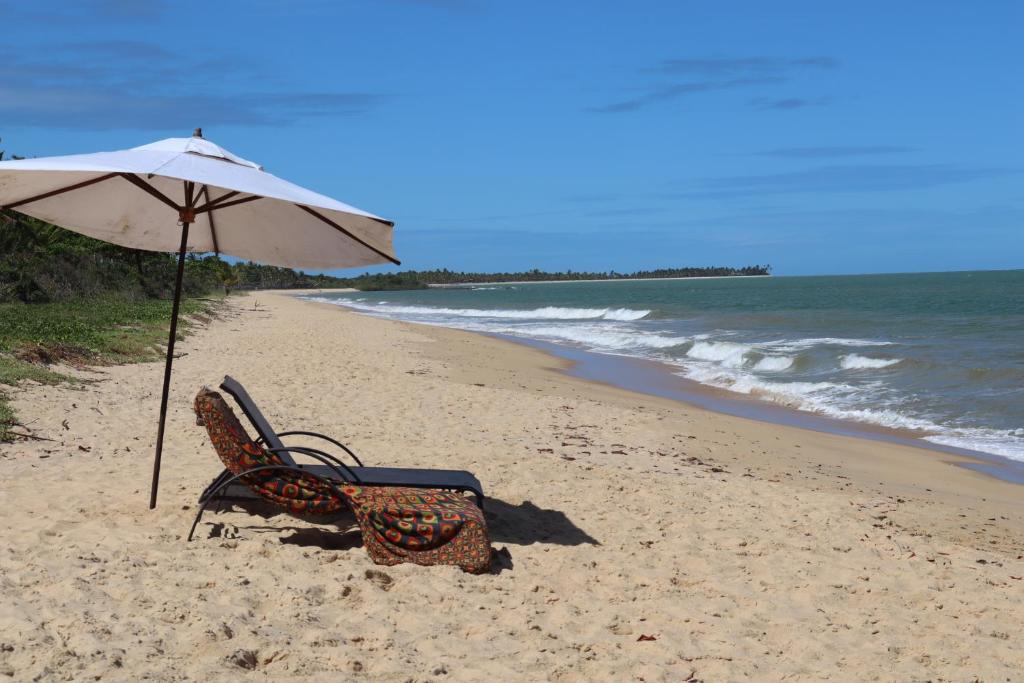 圣安德烈Pousada Colmeia - Praia de Santo André, Bahia的海滩上的一把椅子和一把遮阳伞