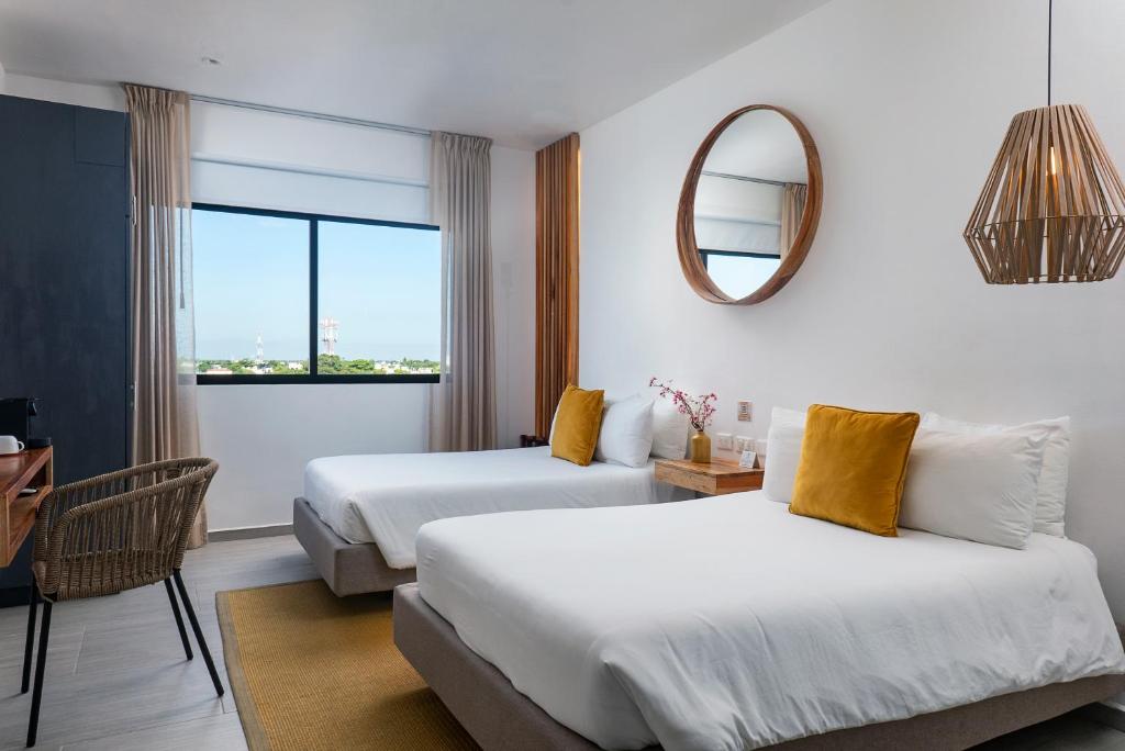 普拉亚卡门Balkon Boutique Hotel的酒店客房,设有两张床和镜子