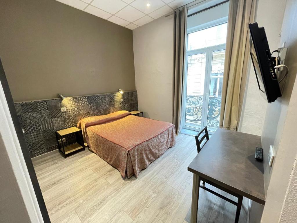 蒙彼利埃德拉柯美迪酒店的一间卧室配有一张床、一张桌子和一个窗户。