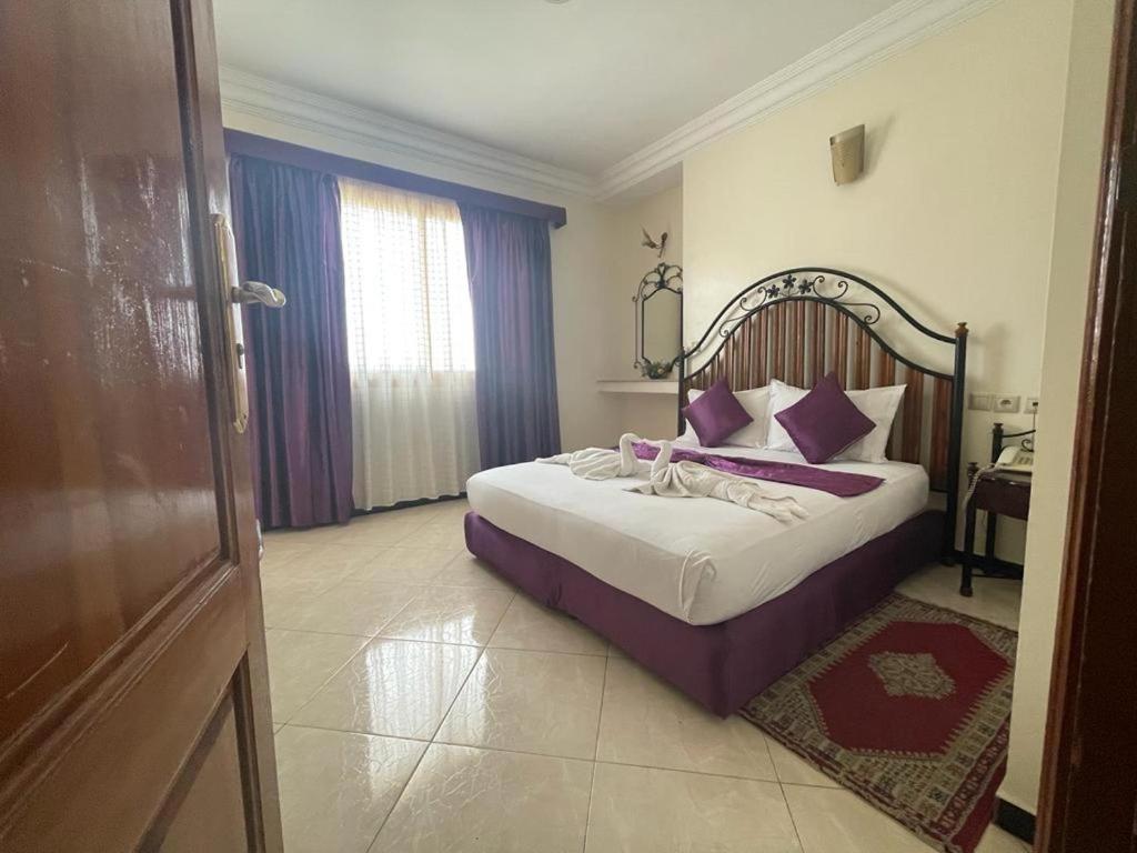 非斯佩尔拉酒店的一间卧室配有一张带紫色枕头的大床