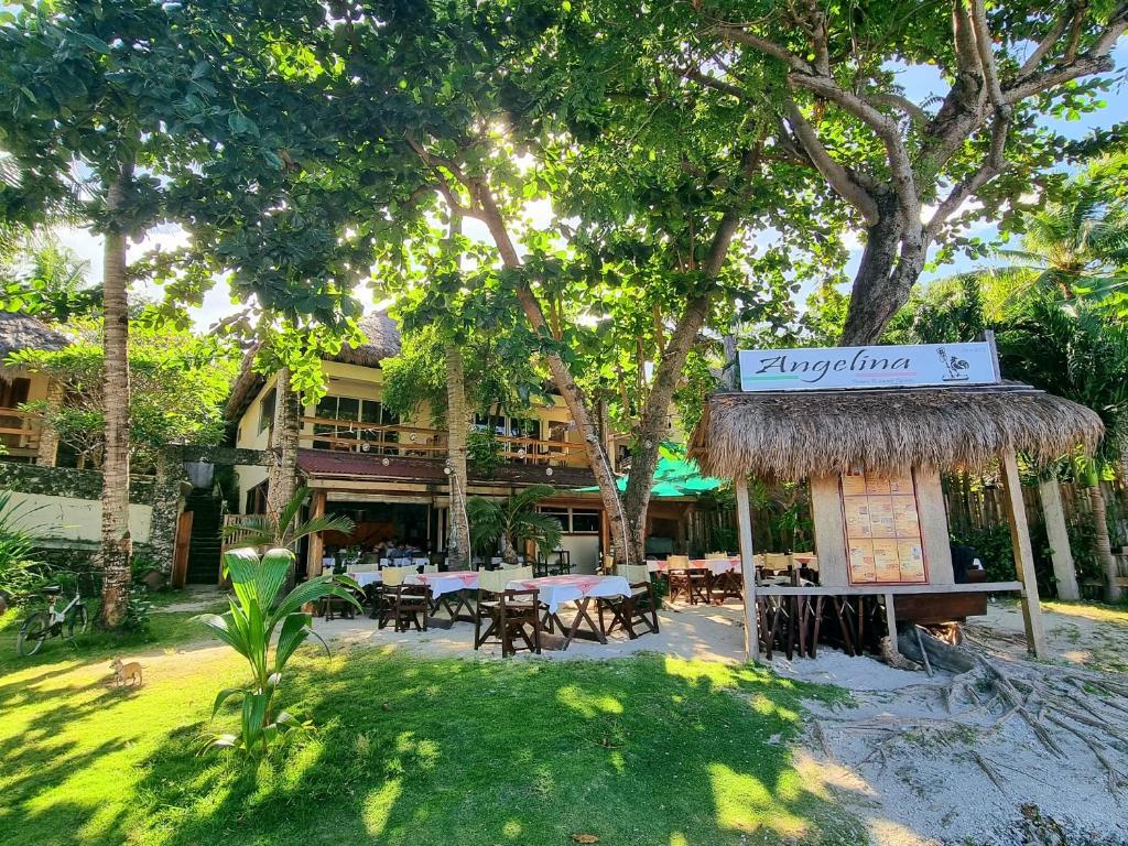 马拉帕斯加Angelina Beach Resort & Italian Restaurant Malapascua的庭院内带桌椅的餐厅