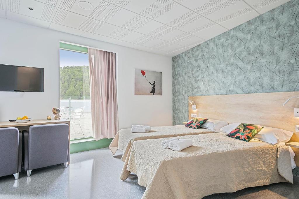 贝古斯Les Begues Apartments的酒店客房设有两张床和电视。