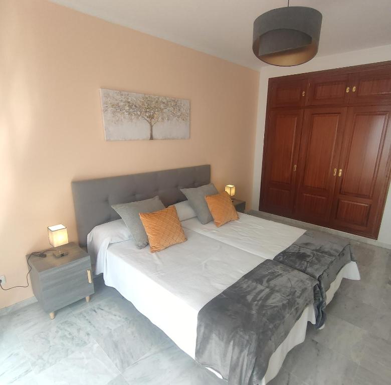 马贝拉Sanpedro Apartamentos Marbella的卧室配有带橙色枕头的大型白色床