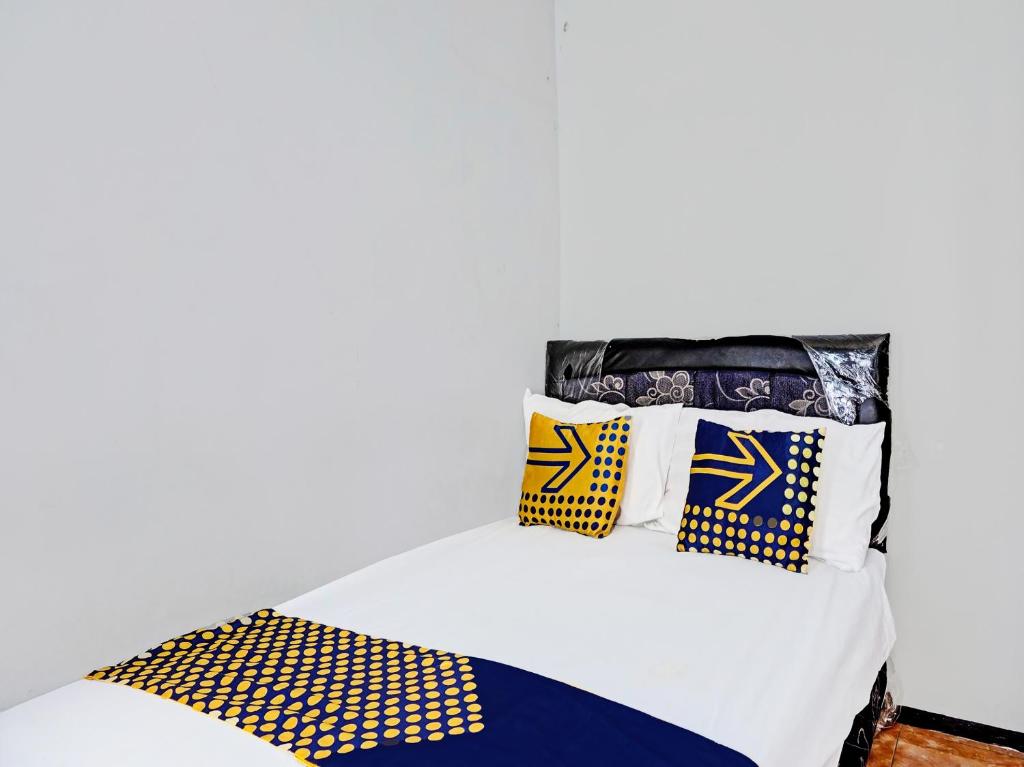玛琅SPOT ON 1711 Serayu Sumbersari Residence的一张白色的床,上面有黄色和蓝色的枕头
