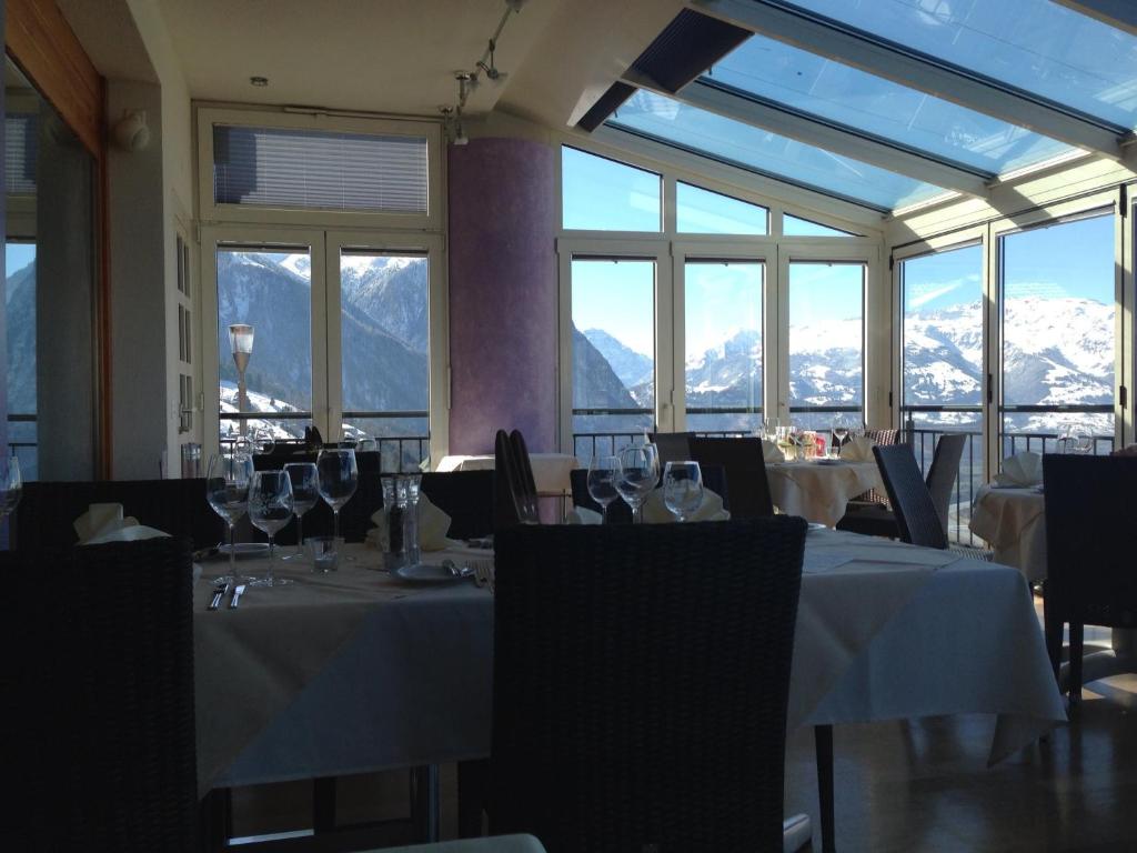 特里森贝格库尔姆餐厅和酒店的餐厅配有桌椅,位于山脉的背景中