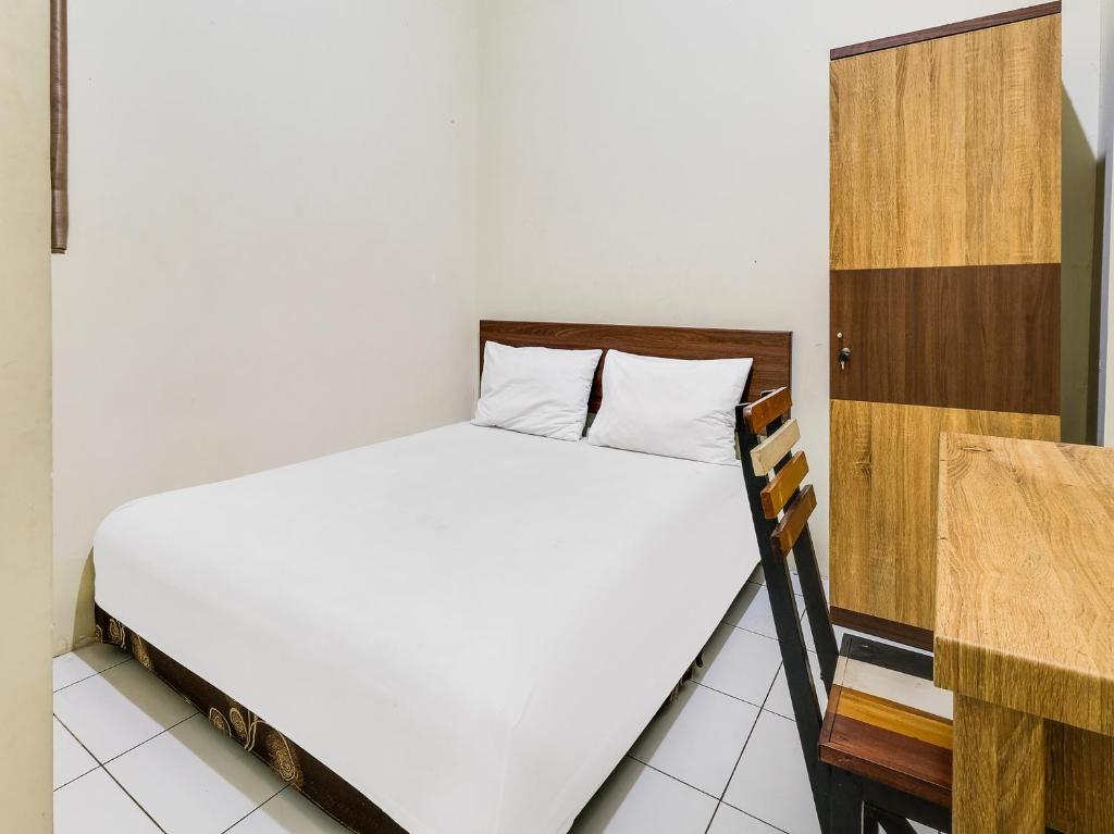 三宝垄SPOT ON 2451 Camel Residence的卧室配有白色的床和木制橱柜。