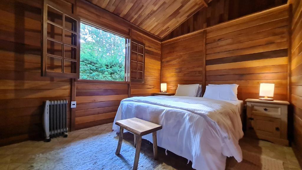 蒙特韦尔迪Chalé Arado 313的一间卧室配有一张带木墙和窗户的床。