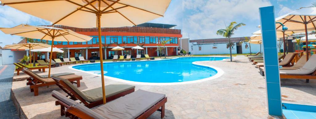 上钦查Hotel Resort Thiago的一座带椅子和遮阳伞的游泳池位于一座建筑旁边
