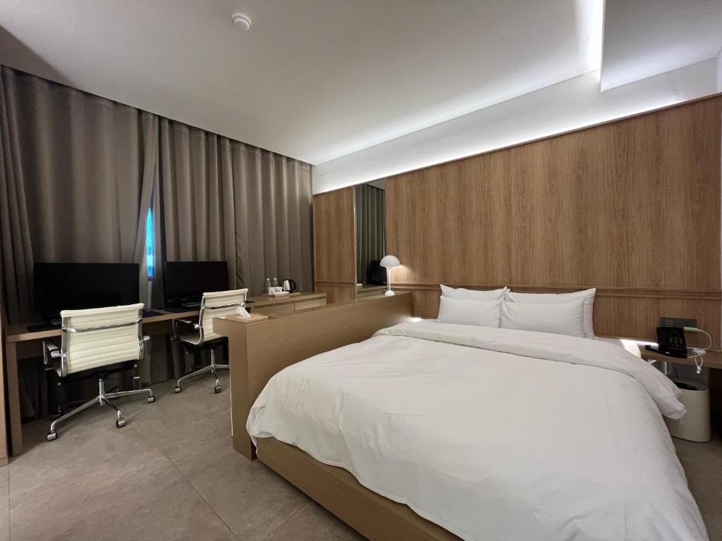 坡州市From H Sodo Hotel Paju的一间卧室配有一张床、一张桌子和一台电脑