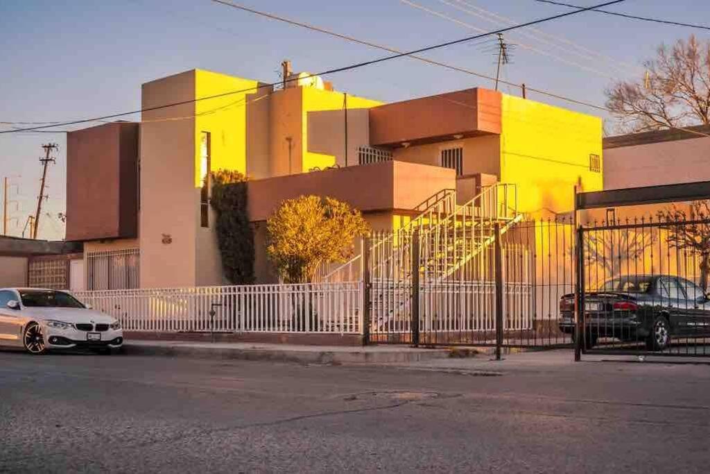 华雷斯城Departamento con Amplia Terraza en Excelente Zona的一座黄色的建筑,前面有汽车停放
