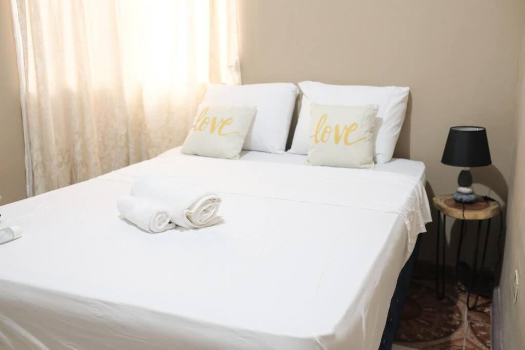 科马亚瓜Casco histórico Demeter的一张白色的床,上面有情人枕头