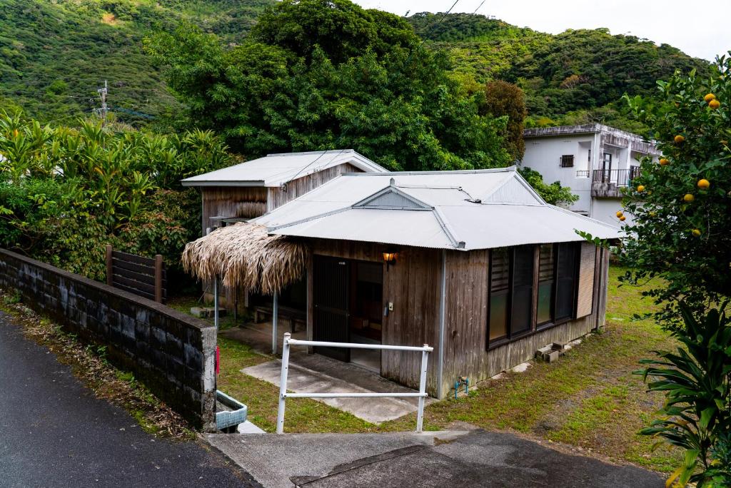 奄美ゲストハウス ハルの家的路边有草屋顶的小房子