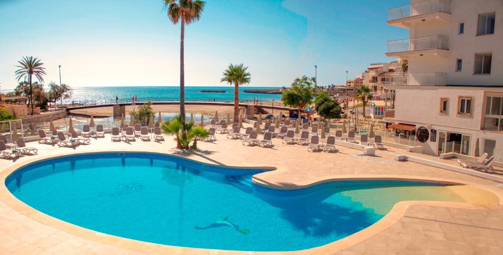 西洛特摩里亚海滩公寓式酒店的一个带椅子的游泳池,背景是大海