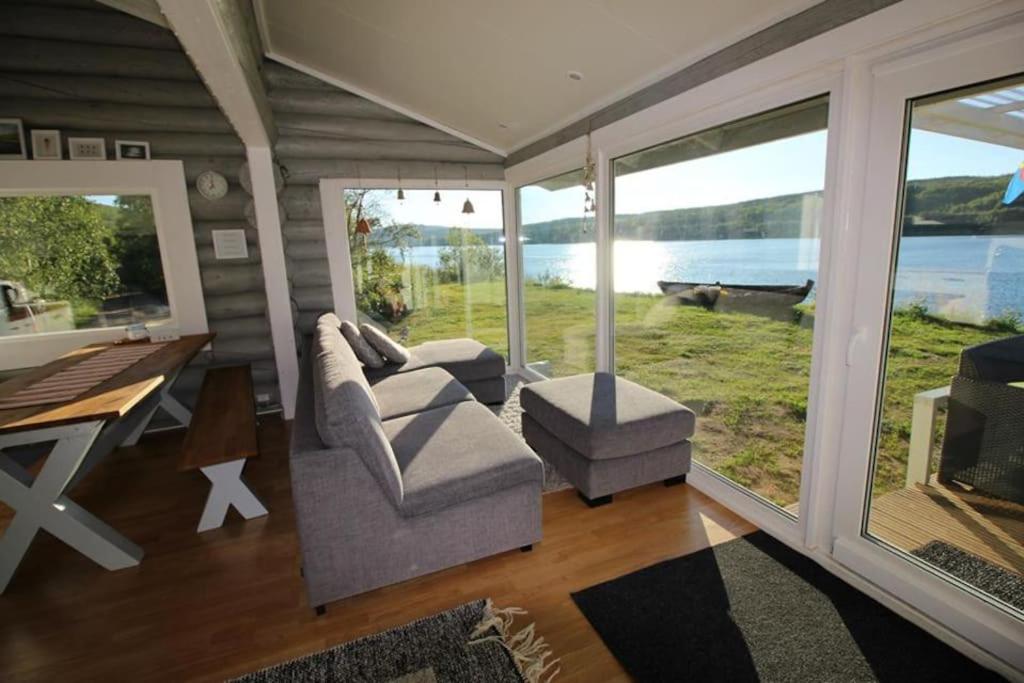 NuorgamBeautiful riverside cottage with sauna的带沙发、桌子和窗户的客厅
