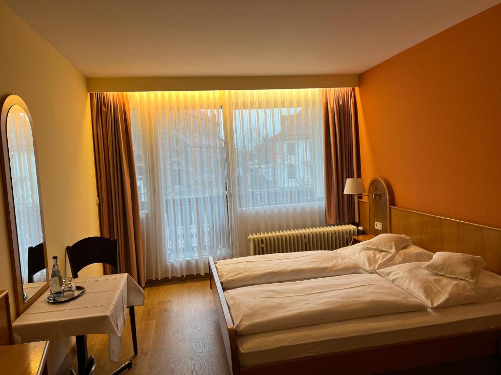 胡根尔舍姆Hotel Schwan的一间卧室配有一张床、一张桌子和一个窗户。