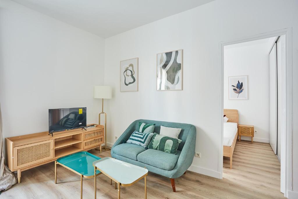 塞纳河畔讷伊Residence Neuilly Bois de Boulogne by Studio prestige的客厅配有蓝色椅子和电视