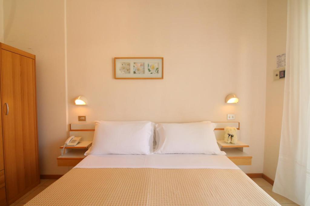里米尼Hotel Soave的一间卧室配有一张带两个白色枕头的床