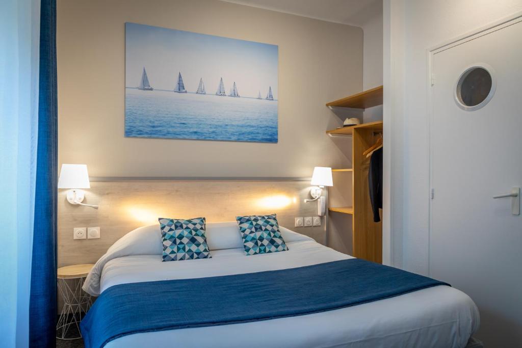洛里昂Logis REX HOTEL Lorient的一间卧室配有一张带两个蓝色枕头的床
