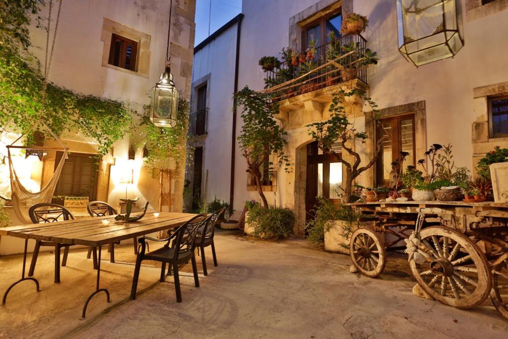 锡拉库扎阿拉朱德卡酒店的庭院配有木桌、椅子和马车。