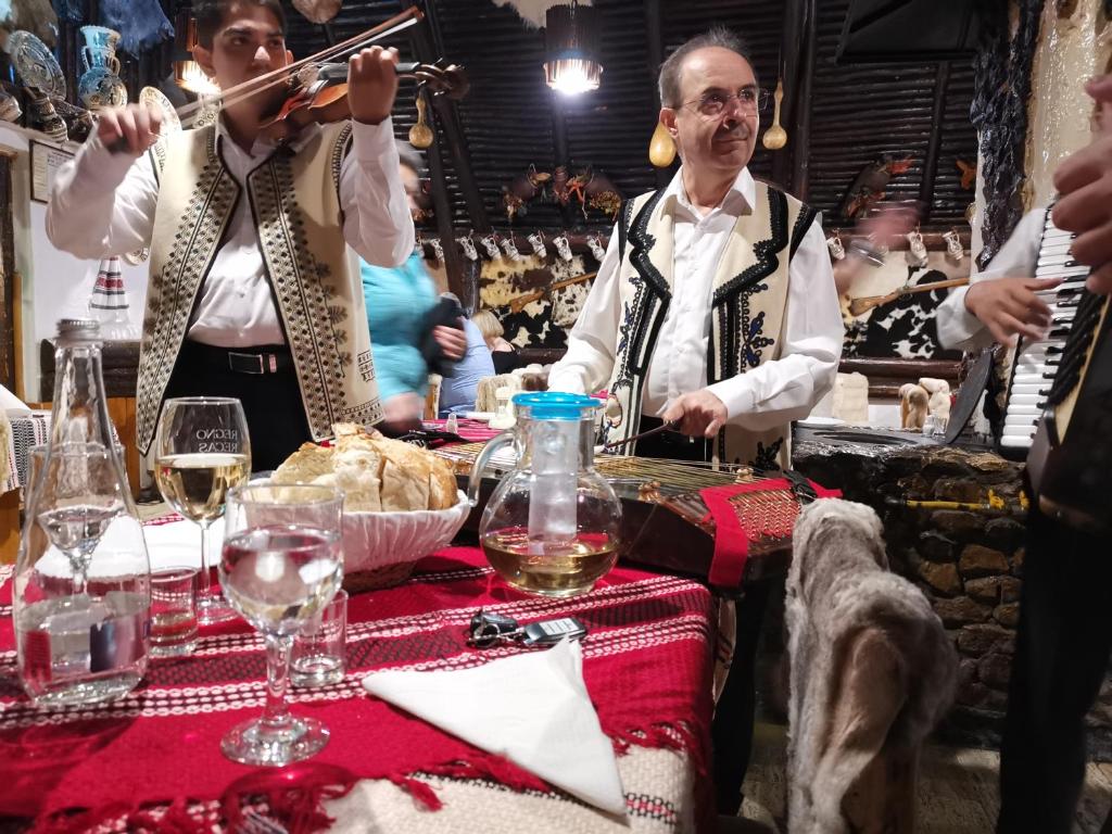 波亚纳布拉索夫Cabana Fantanita cu Brazi的两个男人在桌子上玩乐器,戴着酒杯