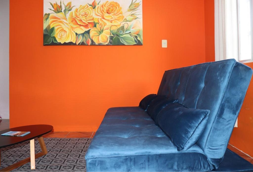 纳韦甘蒂斯Casa de praia da Kenna, centro的客厅里设有蓝色的沙发,拥有橙色的墙壁