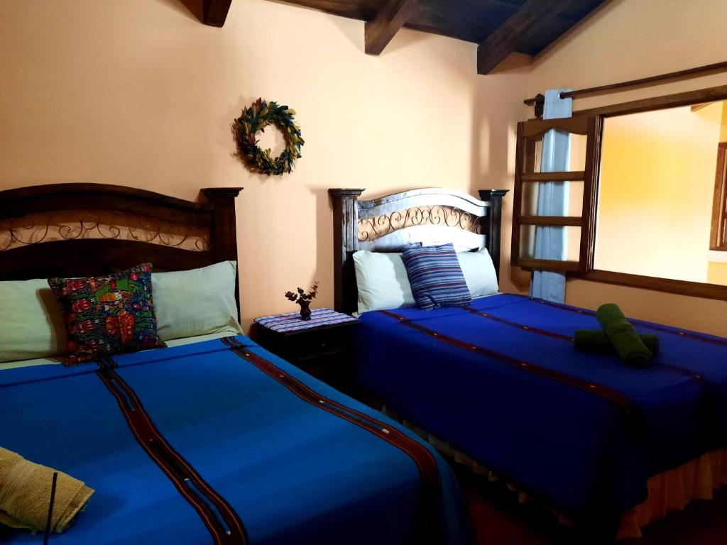 危地马拉安地瓜Hotel Casa Sofia的一间卧室配有两张带蓝色床单和镜子的床