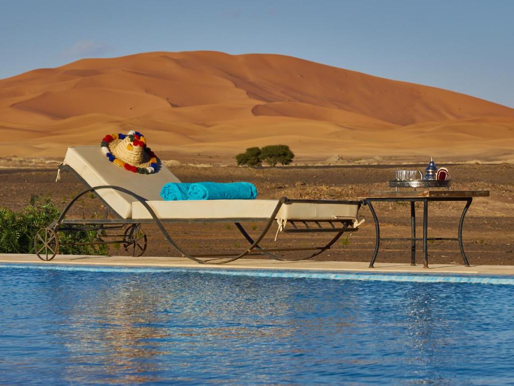 梅尔祖卡马杜摩洛哥传统庭院的沙漠中游泳池畔的一张床和桌子