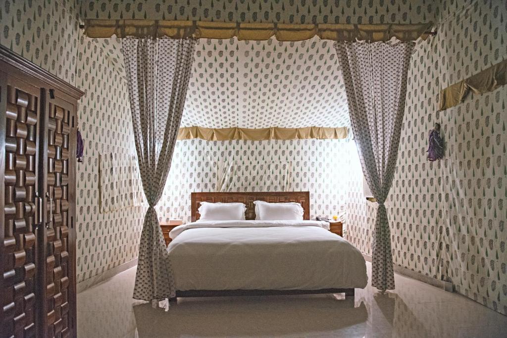 布什格尔Atithi Camp & Resort的一间卧室配有一张带天蓬的大床
