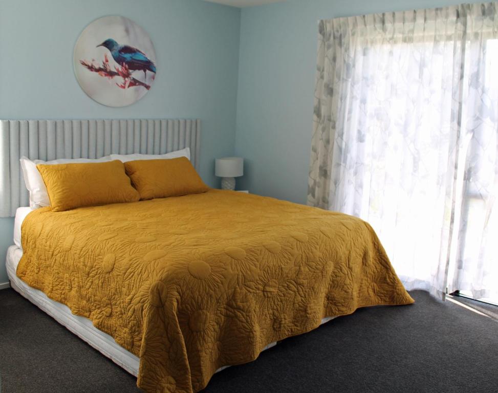 布伦海姆Marlborough Wine Country B&B的一间卧室配有一张带黄色毯子和窗户的床