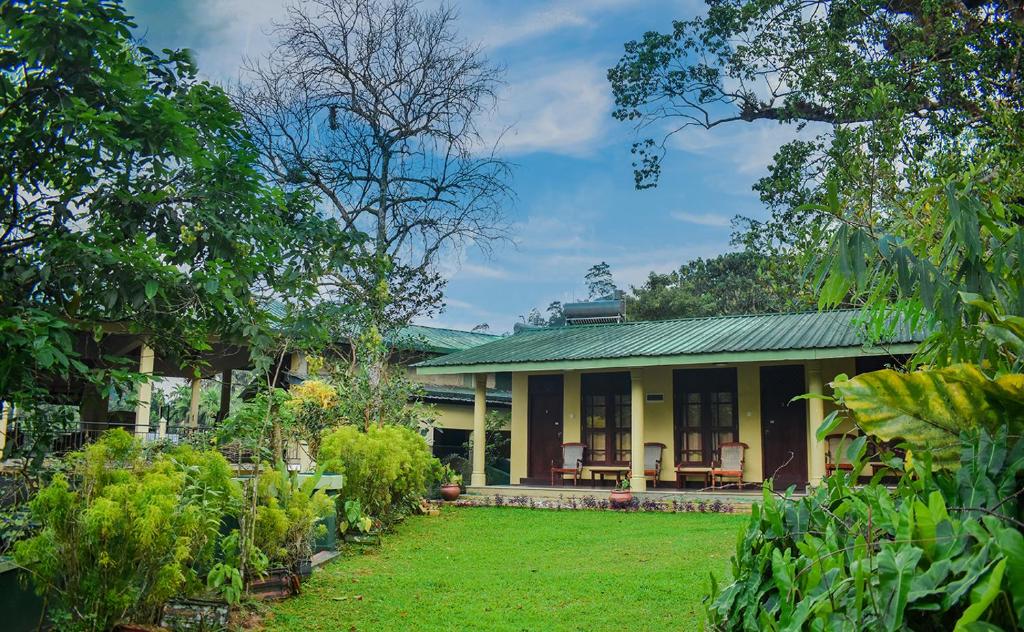 KudaweBlue Magpie Lodge Sinharaja的一座带绿色屋顶和庭院的房子