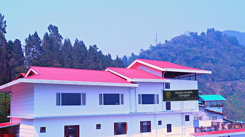 甘托克ShriGo Hotel Gangtok的一座有红色屋顶的建筑,背景是一座山