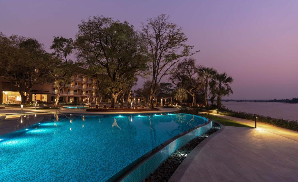 利文斯顿Radisson Blu Mosi-oa-Tunya Livingstone Resort的夜间在湖边的大型游泳池