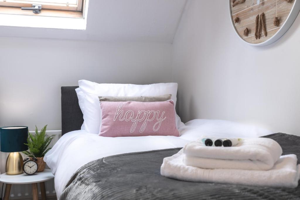 奇切斯特Chichester retreat house with free parking的一间卧室配有一张带粉红色枕头的床和2条毛巾