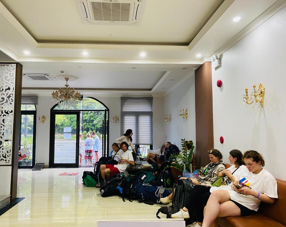 下龙湾De Charm Hạ Long Hotel的一群坐在大堂看电话的人