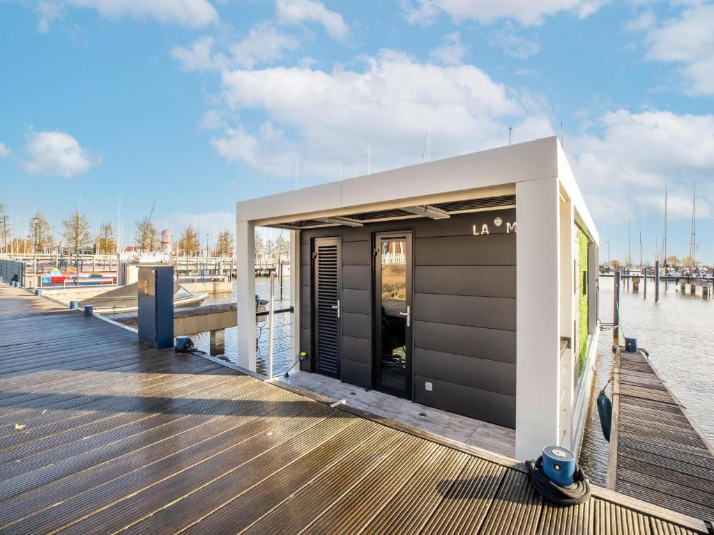 福伦丹Inviting houseboat in Volendam with shared pool的水边码头上的一座小建筑