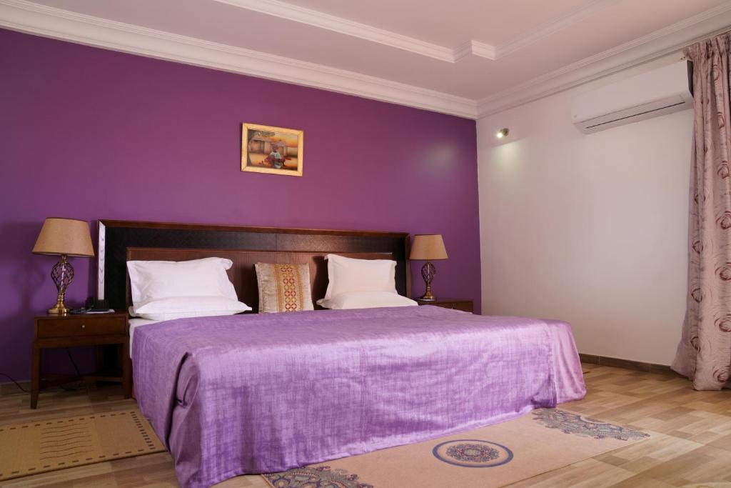 达喀尔拉斐尔特2号酒店的紫色卧室,配有一张带紫色毯子的床