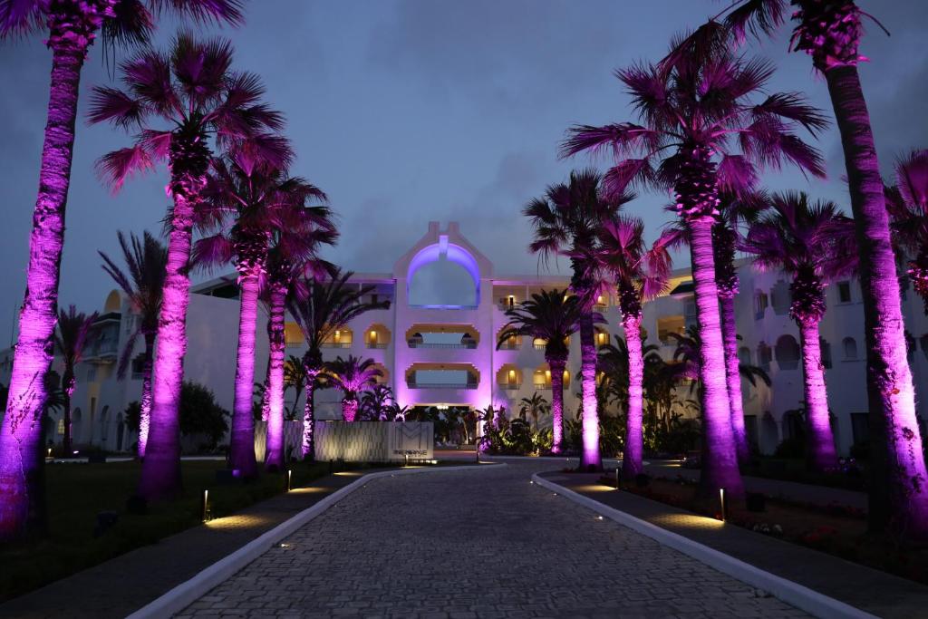 哈马马特The Mirage Resort & SPA的一座棕榈树和紫色灯的建筑
