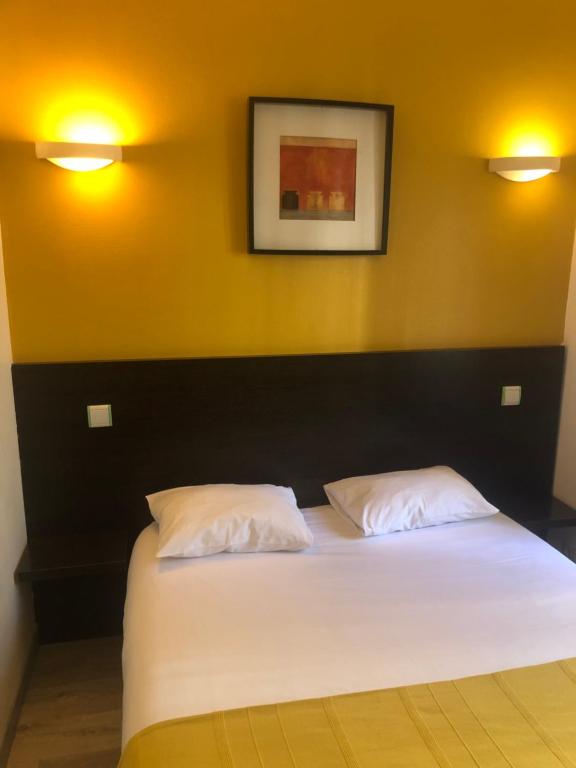 第戎巴黎酒店的一间卧室配有一张带两个白色枕头的床