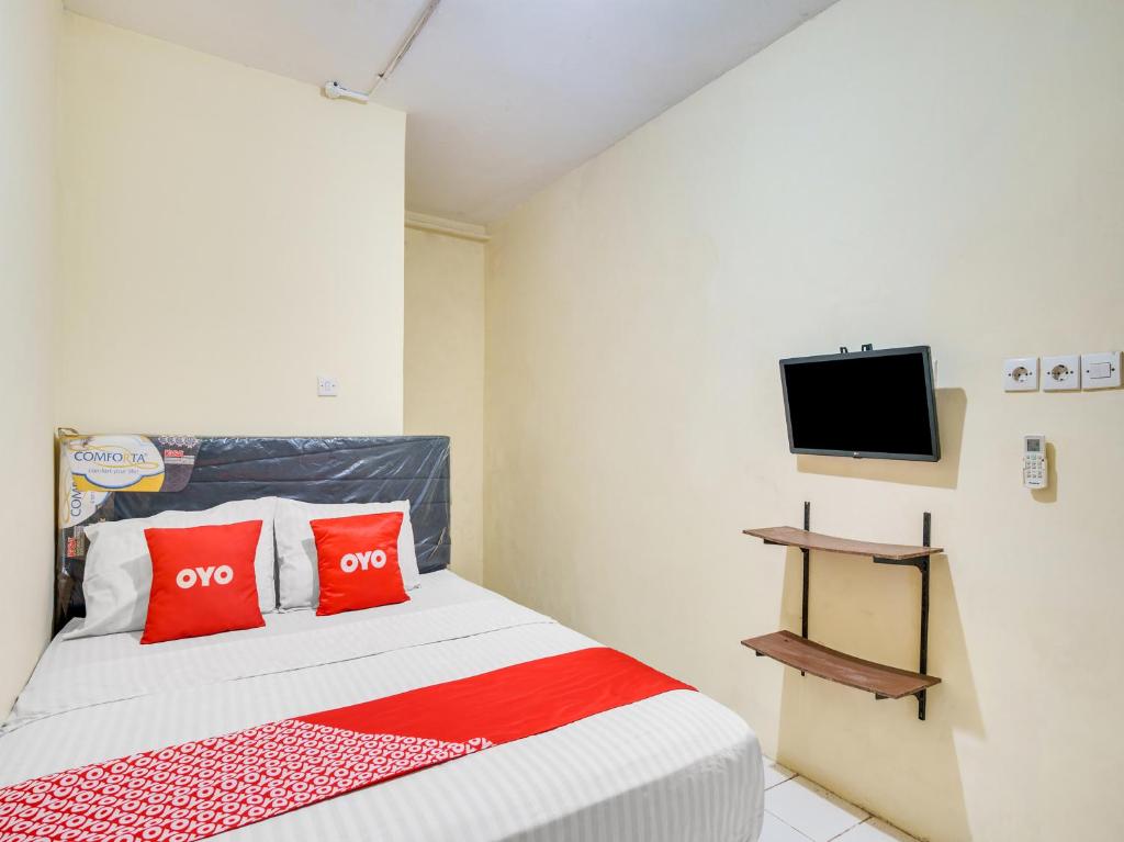 雅加达SUPER OYO 591 Mn Residence Syariah的一间卧室配有一张带红色枕头的床和一台电视。