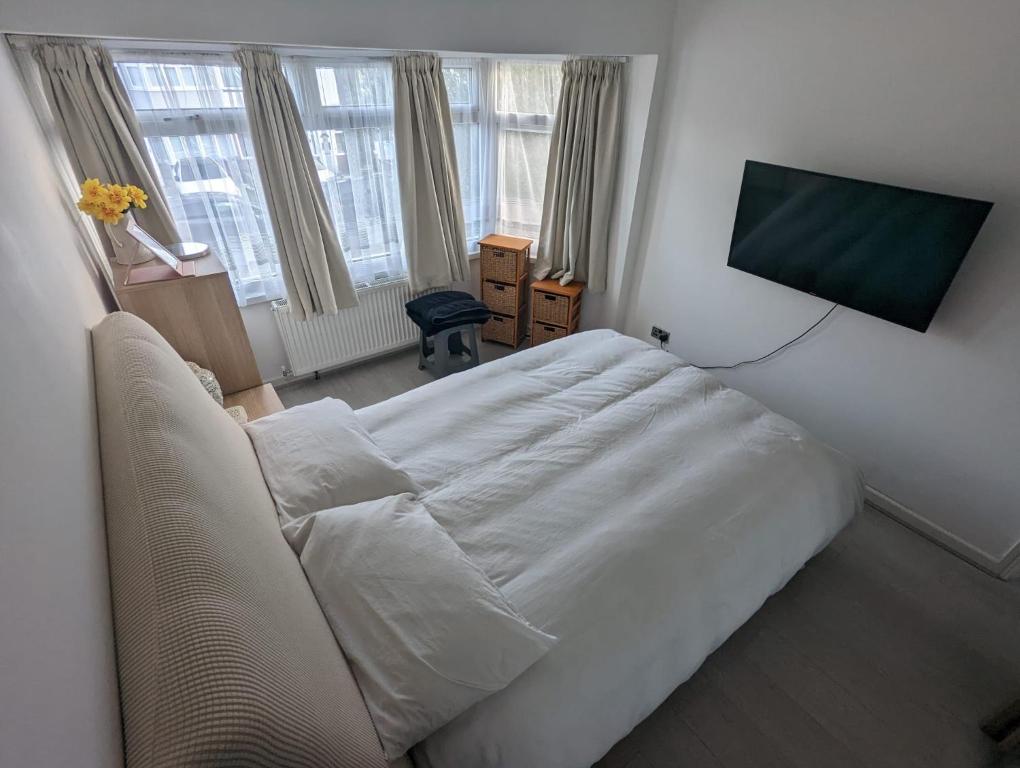 埃德蒙顿Spacious 2 bedroom house with garden的卧室配有白色的床和平面电视。