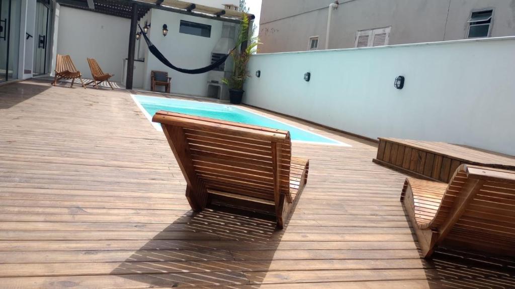 Balneário GaivotasThe Guest House hostel的一个带两把椅子的游泳池和一个游泳池
